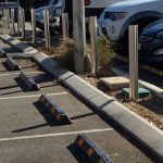 steel bollards in a parking lot with parked cars