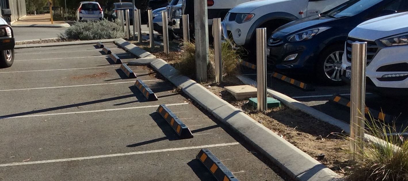 steel bollards in a parking lot with parked cars